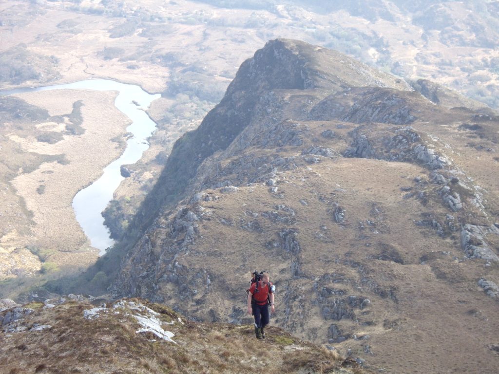 Mike Jones hiking a ridgeline above a lake at Eagle's Nest, Killarney