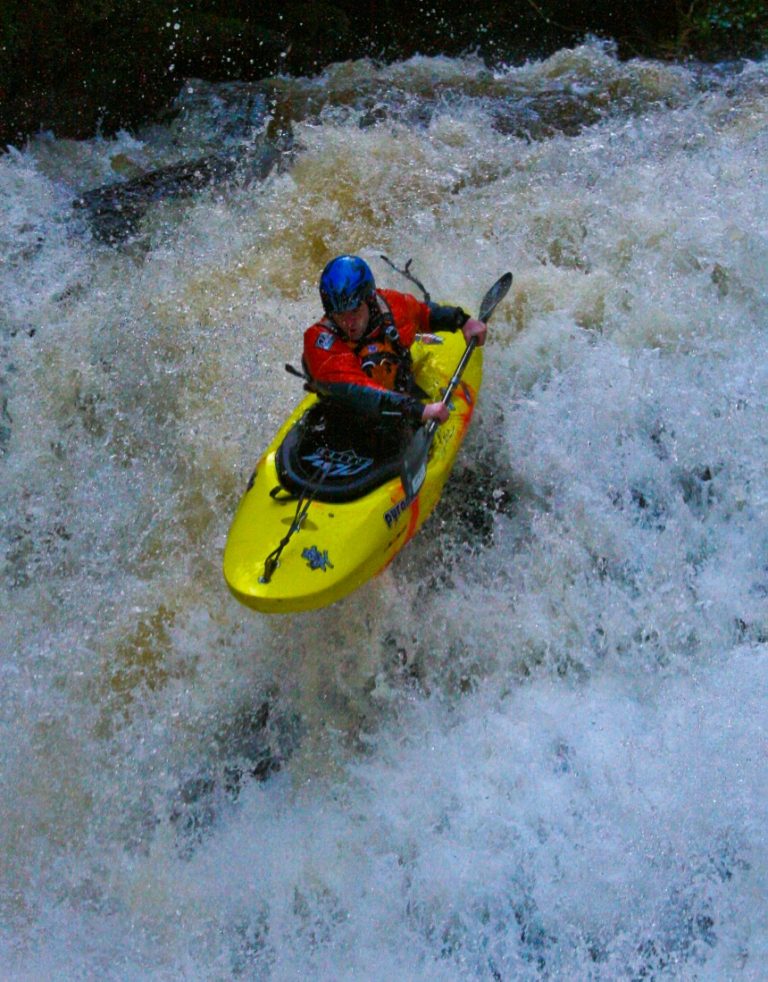 A kayaker dropping a waterfall at Clare Glens, fully in the flow